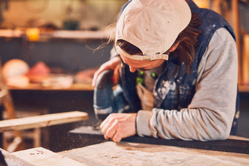 Male carpenter working on old wood in a retro vintage workshop.