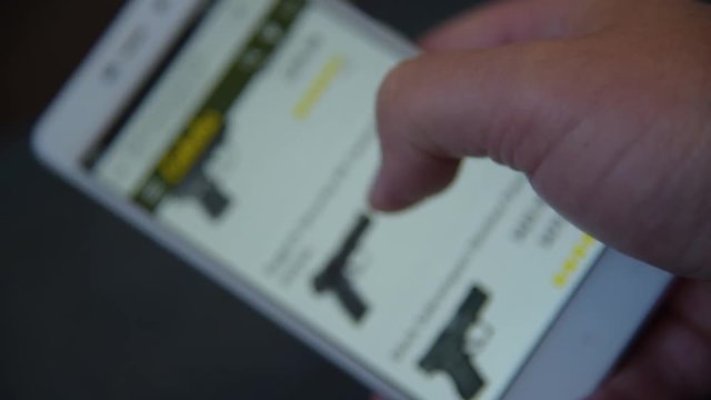 A man looking and chooses a weapons to buy on the site.