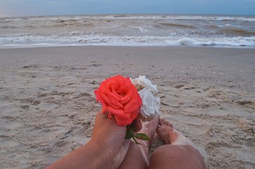 evening on the beach, tanned legs, cozy evening, romantic mood, flowers in hand, female legs, thoughts of the sea