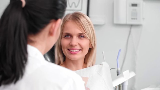 Conversation between smiling woman and dentist in dentist's clinic