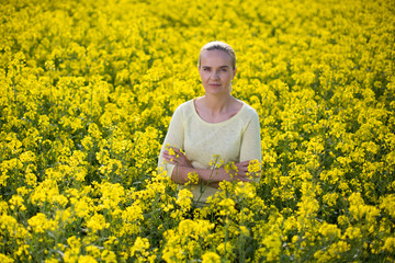 Fototapeta premium Happy woman on blooming rapeseed field in springin yellow blouse.