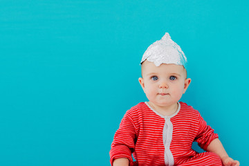 A child in a foil hat sits on a blue background