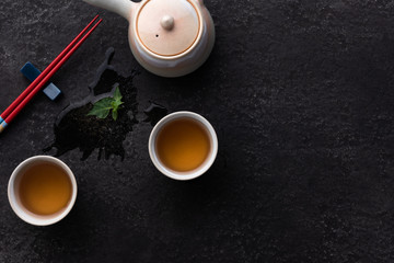Obraz na płótnie Canvas tea composition with ceramic tea cups and teapot on dark stone background