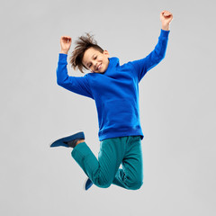 childhood, expressions and people concept - portrait of smiling boy in blue hoodie jumping over...
