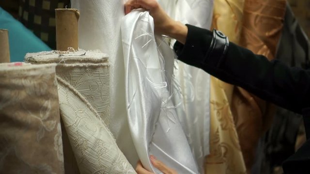 Hands examine the material in a fabric shopIn a fabric textile shop, a designer uses his hand to touch and feel a material to determine if it is suitable for use in his project.