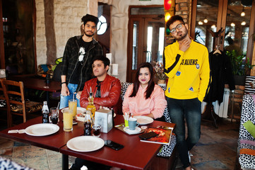 Group of asian friends sitting cafe. Happy indian people having fun together, sitting on couch.