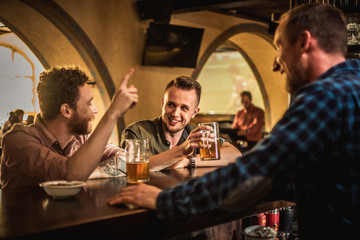 Cheerful friends drinking draft beer in a pub