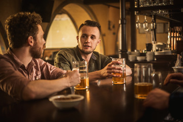 Cheerful friends drinking draft beer in a pub