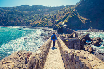 A man walks over the bridge to the island of Gaztelugatxe. Bay of Biscay, Basque Country, Spain, Europe