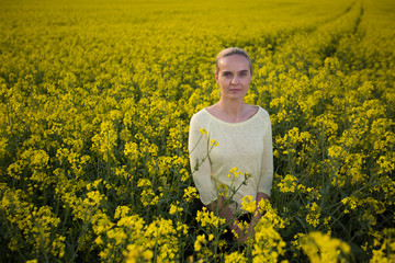 Fototapeta premium Happy woman on blooming rapeseed field in springin yellow blouse.