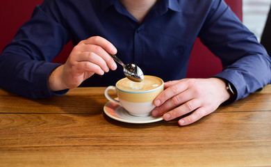 Man holding a cup of cappuccino.