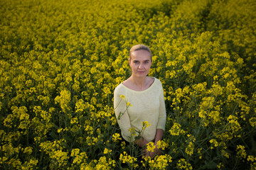 Fototapeta premium Happy woman on blooming rapeseed field in springin yellow blouse.