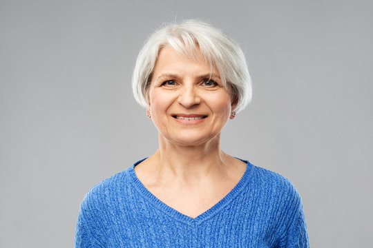 Old People Concept - Portrait Of Smiling Senior Woman In Blue Sweater Over Grey Background