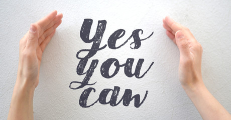 Female hands putting in brackets text YES YOU CAN, motivational concepts