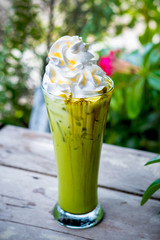 Ice Matcha green tea with whipped cream on wooden table