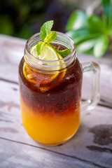 Orange black coffee with ice in glass on wooden table