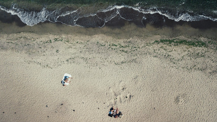 Top view of the sea, ocean. Vacationers on the sand by the water. Photographed from the drone