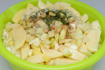 sliced raw potatoes seasoned in a bright green deep dish