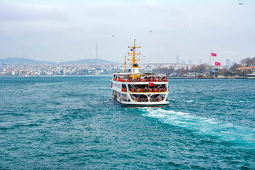 Fototapeta premium Muslim architecture and water transport in Turkey - Beautiful View touristic landmarks from sea voyage on Bosphorus. Cityscape of Istanbul at sunset - old mosque and turkish steamboats, view on Golden