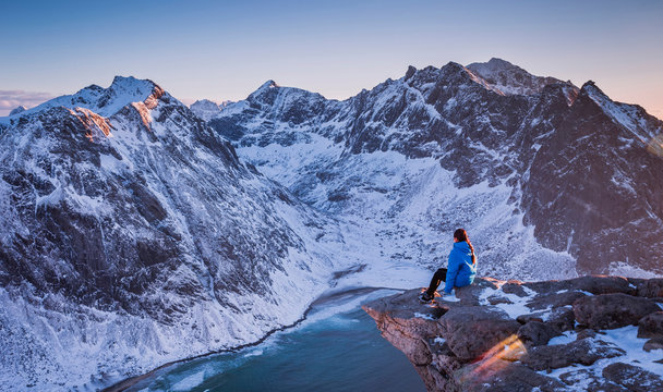 The girl enjoys the magnificent scenery of the mountains and the ocean, Ryten Mountain, Norway