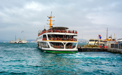 Obraz premium Muslim architecture and water transport in Turkey - Beautiful View touristic landmarks from sea voyage on Bosphorus. Cityscape of Istanbul at sunset - old mosque and turkish steamboats, view on Golden