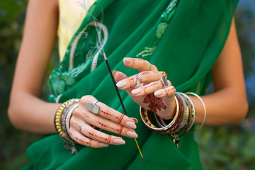 Beautiful woman in traditional Muslim Indian wedding green sari dress hands with henna tattoo...