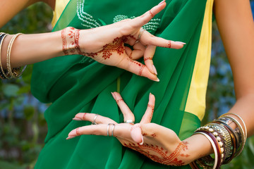 Beautiful woman in traditional Muslim Indian wedding green sari dress with henna tattoo jewelry and bracelets do hands nritta odissi Samyuta hastas dance Movement Alapadma Bramara Concept background