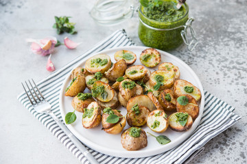 Baked potatoes in rustic style with green pesto sauce