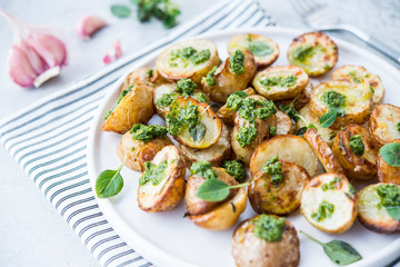 Baked potatoes in rustic style with green pesto sauce