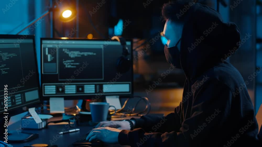Poster cybercrime, hacking and technology concept - asian male hacker in mask writing code or using compute