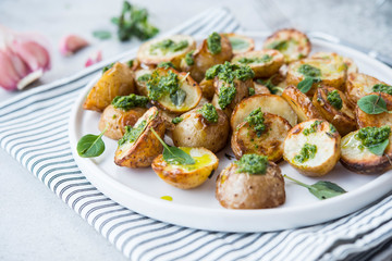 Baked potatoes in rustic style with green pesto sauce