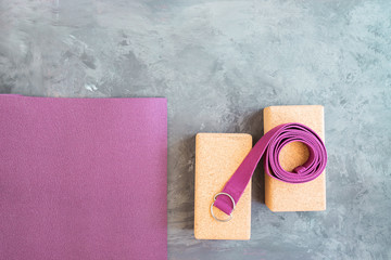 Open yoga mat, two cork  blocks  and yoga belt on grey cement  background. Start yoga practice...