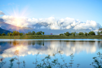 Lovers in red jackets are standing and looking at the mountains with clouds.