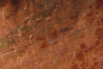 Natural stone of red color with yellow and burgundy streaks and cracks