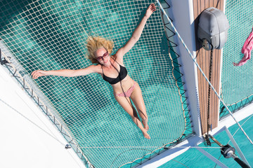 Womanin bikini tanning and relaxing on a summer sailin cruise, lying in hammock of luxury catamaran...