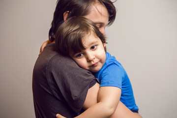 father in the gray shirt holding a son in a blue t-shirt in the hands