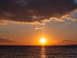 Fototapeta na wymiar Bright orange sunset over the sea - islands on the horizon