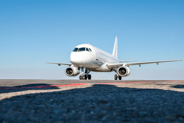 Taxiing a white passenger airplane on the airport apron