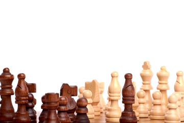 Close-up view of white and black chess pieces on a wooden chessboard in game. Isolated on white background
