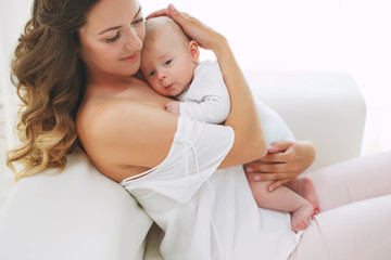 Obraz na płótnie Canvas Young mother holding her newborn child. Mom nursing baby. Woman and new born boy relax. Nursery interior. Mother breast feeding baby. Family at home. Portrait of happy mother and baby 