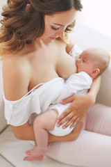 Obraz na płótnie Canvas close up of mother breast feeding her newborn baby girl at home