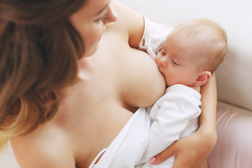 close up of mother breast feeding her newborn baby girl at home