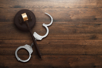 Judge's gavel and handcuffs on wooden background, top view, flat lay. The concept of justice, punishment, judge, corrupt court. copy space