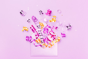 Birthday party explosion concept. Envelope with party streamers and confetti on lilac background....