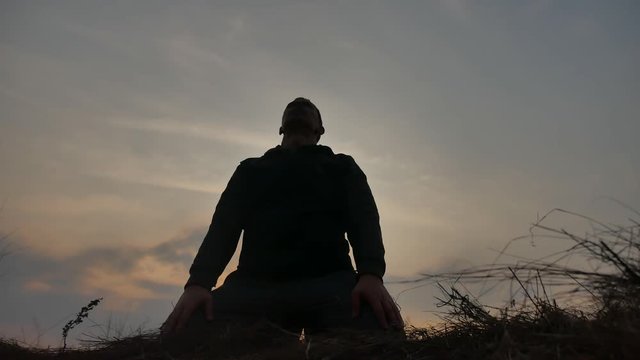 religion concept. silhouette of a male monk engaged in meditation at sunset sunlight. Buddhist lifestyle prayer at sunset healthy way of life nature