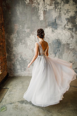portrait of a young beautiful wedding bride in a beautiful stylish dress on a gray background