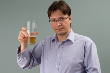 A handsome young man holding a glass of draught lager beer