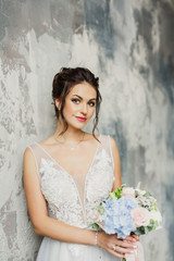 portrait of a young beautiful wedding bride in a beautiful stylish dress on a gray background