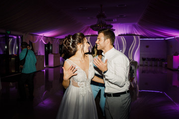 young beautiful wedding couple dancing in a restaurant and having fun bride in beautiful dress groom stylishly dressed