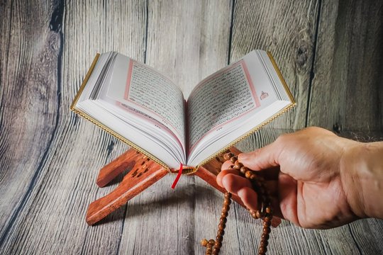 Islamic Concept: The Holy Qoran against wooden background.